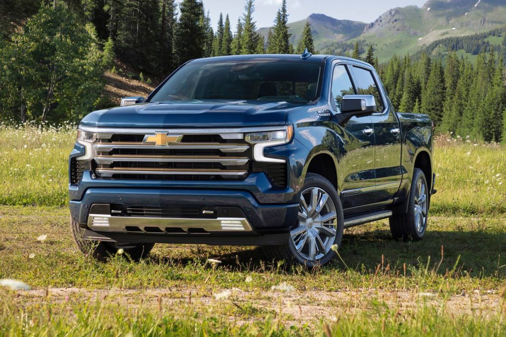Brand new Chevy Blue 2022 Chevrolet Silverado 1500 parked in the middle of a field in a mountainous forest setting.